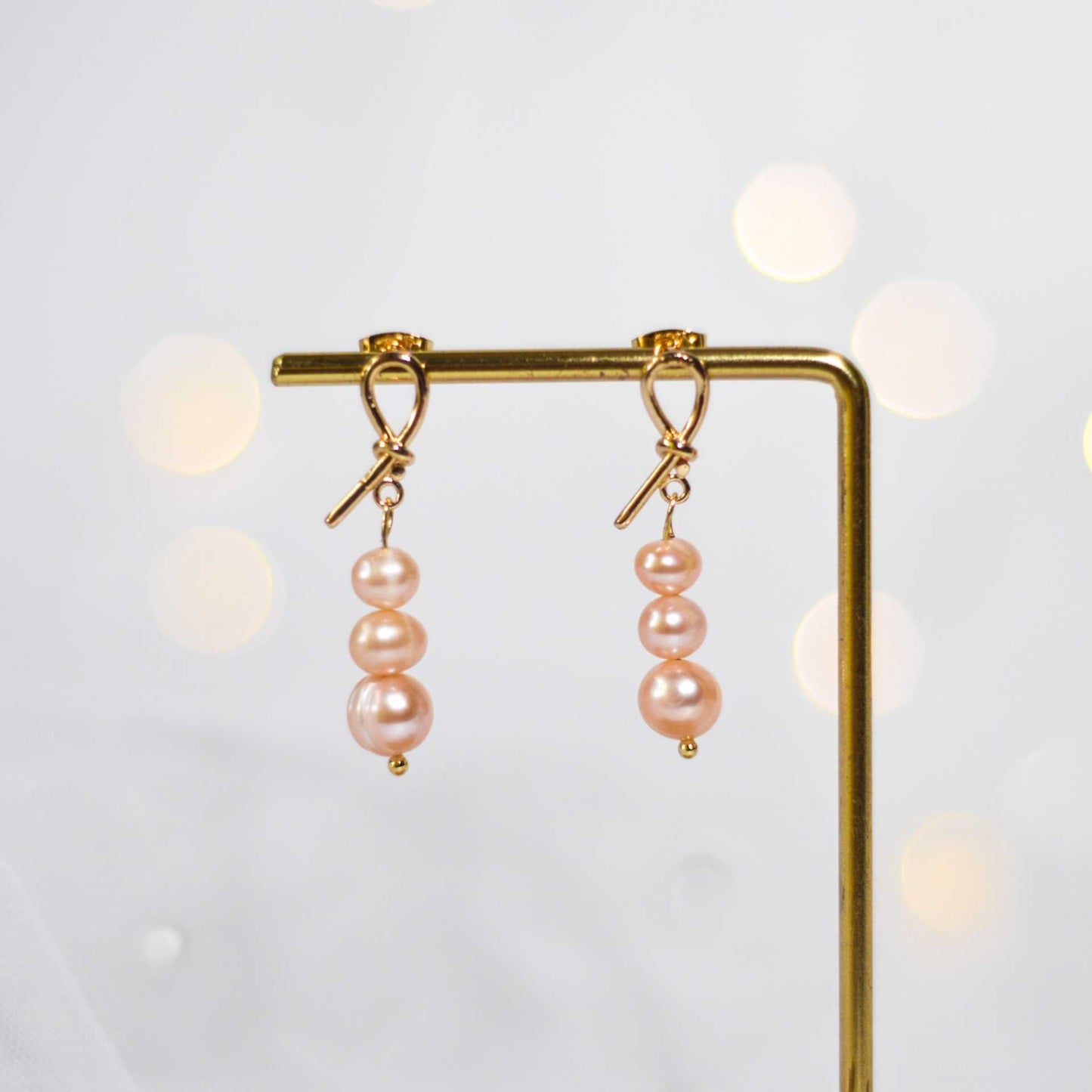 Tiered light pink pearls yellow gold plated dangling knot earrings
