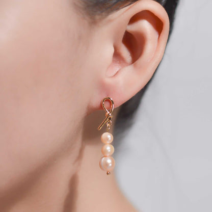Tiered light pink pearls yellow gold plated dangling knot earrings